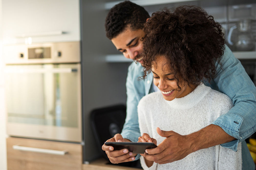 A young couple in their new house looking at a tablet with an online report from their home inspection